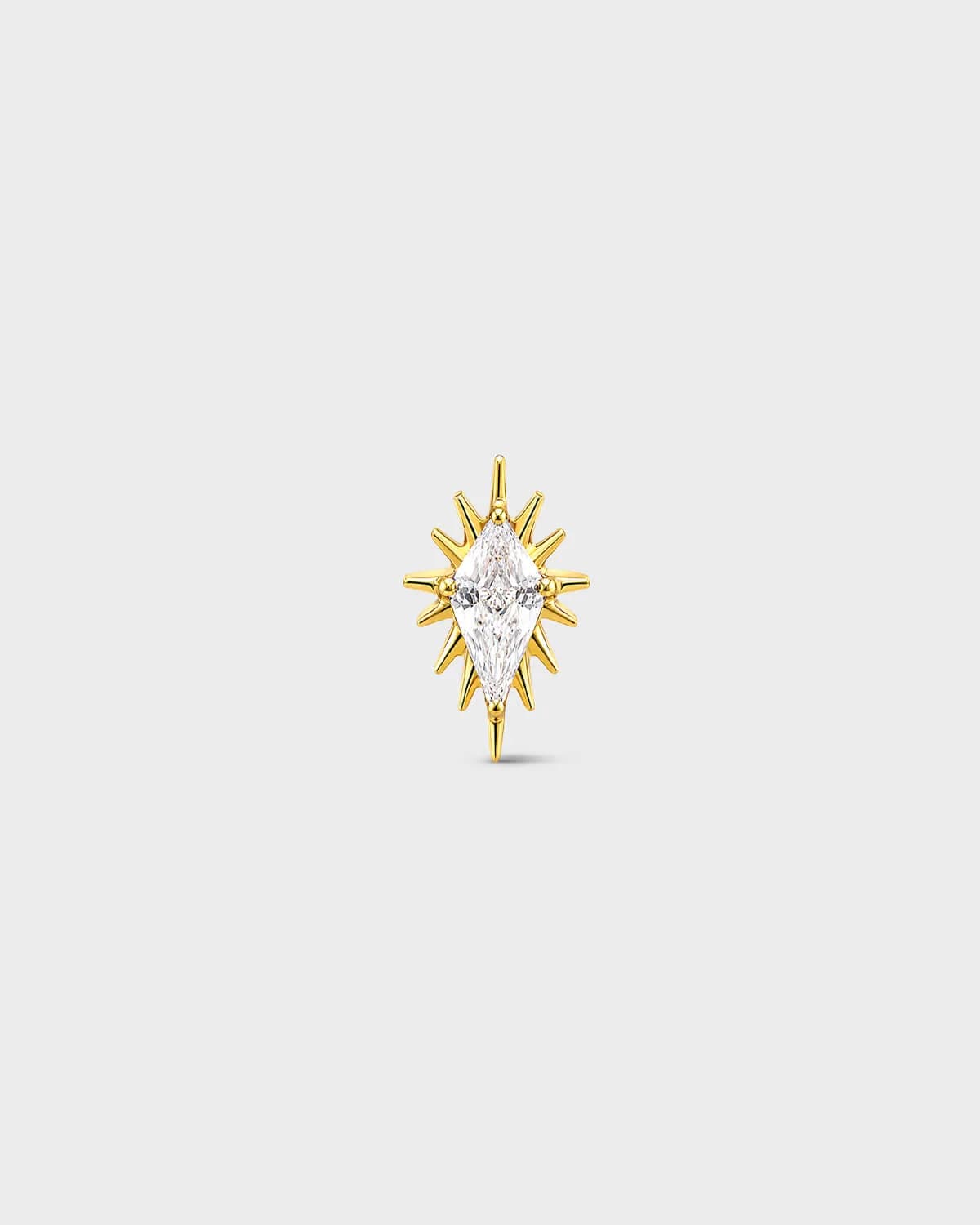 gold titanium threadless end earring with a marquise-cut clear stone set within a sculpted starburst design. On a light grey background.